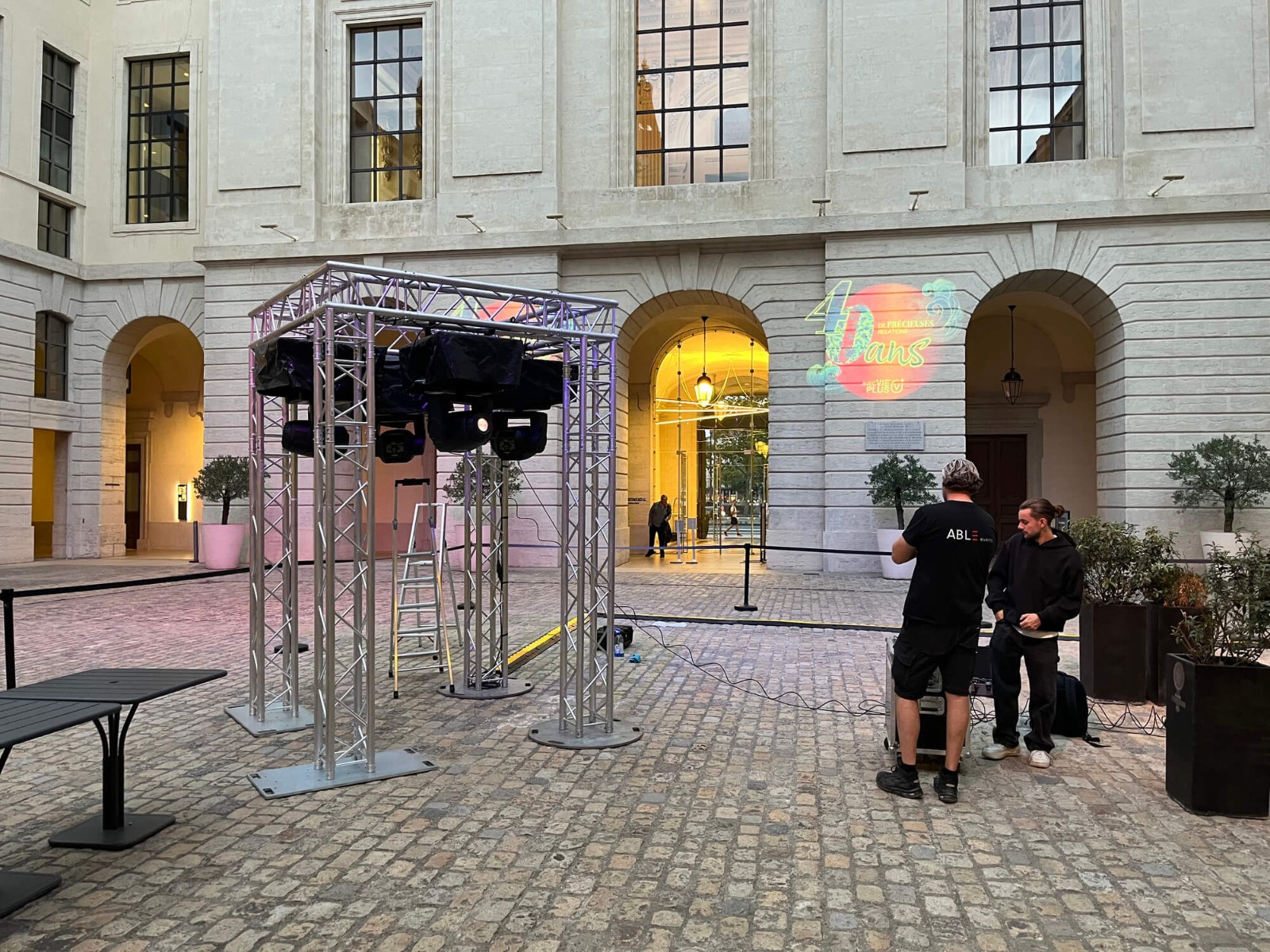 Installation de lyres sur une structure carrée pour projeter 4 gobos sur 4 murs de la cour du Grand Réfectoire à Lyon Les techniciens ABLE events qui installent et configurent les lyres pour la projection de gobo en extérieur dans la cour du Grand Réfectoire à Lyon