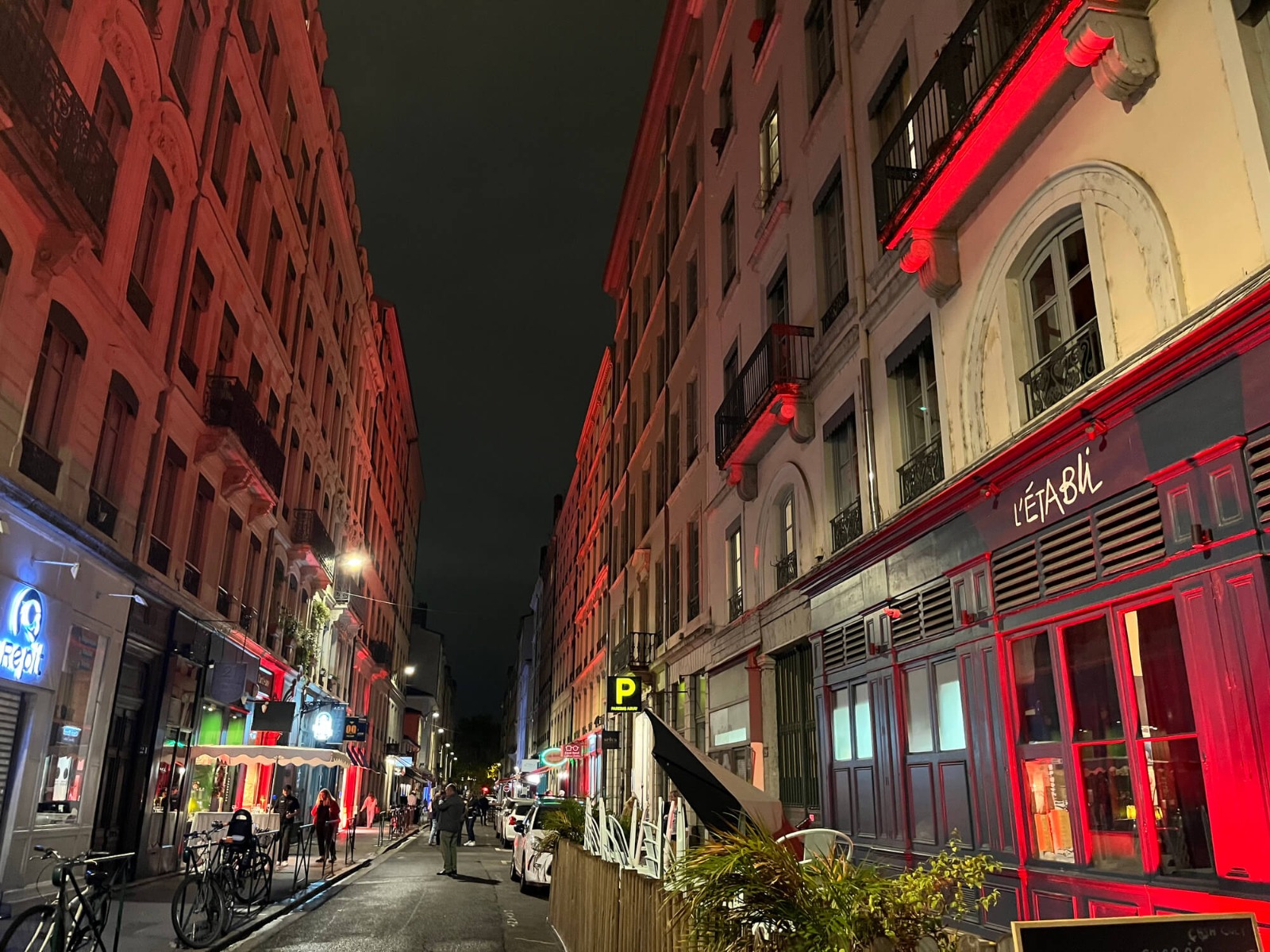 Perspective de la rue Auguste Comte à Lyon de nuit avec façades de boutiques, balcons et devantures soulignés de rouge