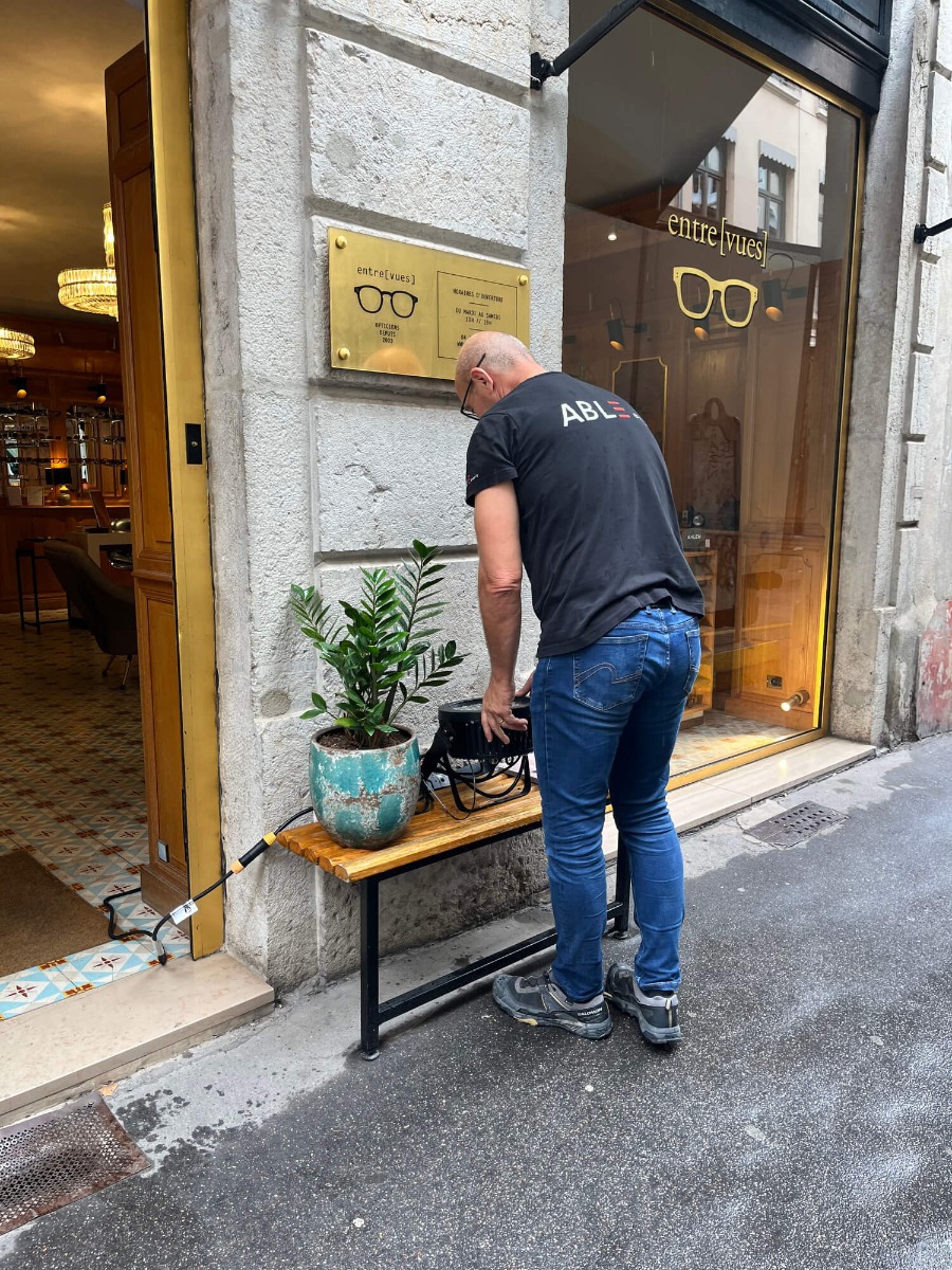 Un technicien qui installe un éclairage devant un magasin rue Auguste Comte pour la soirée Rouge